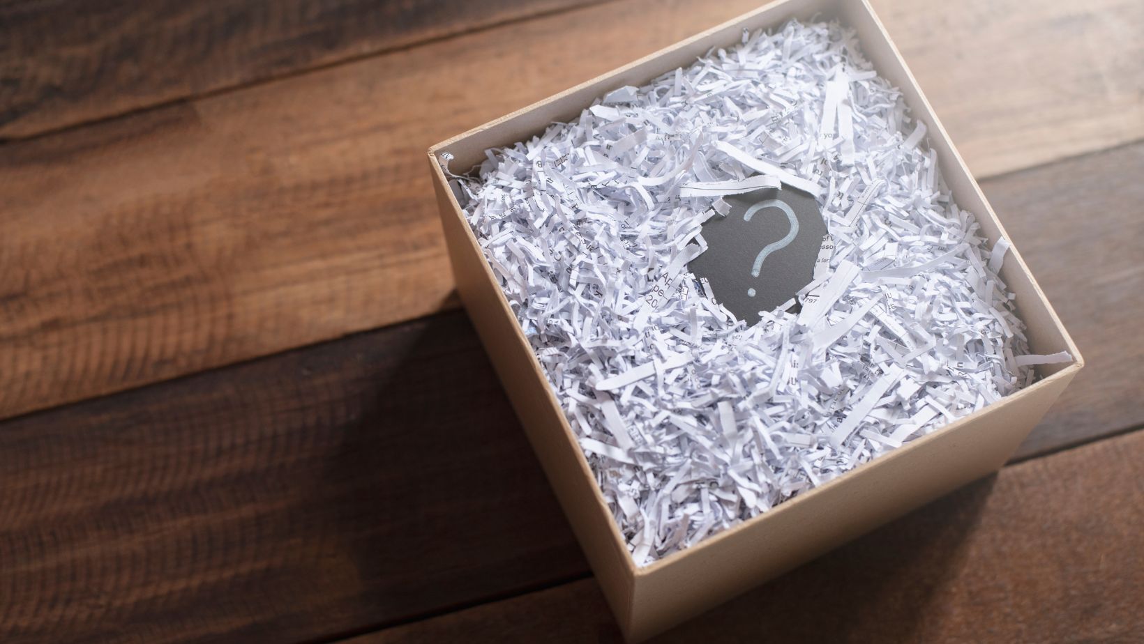 A box with shredded paper with a question mark in the middle.